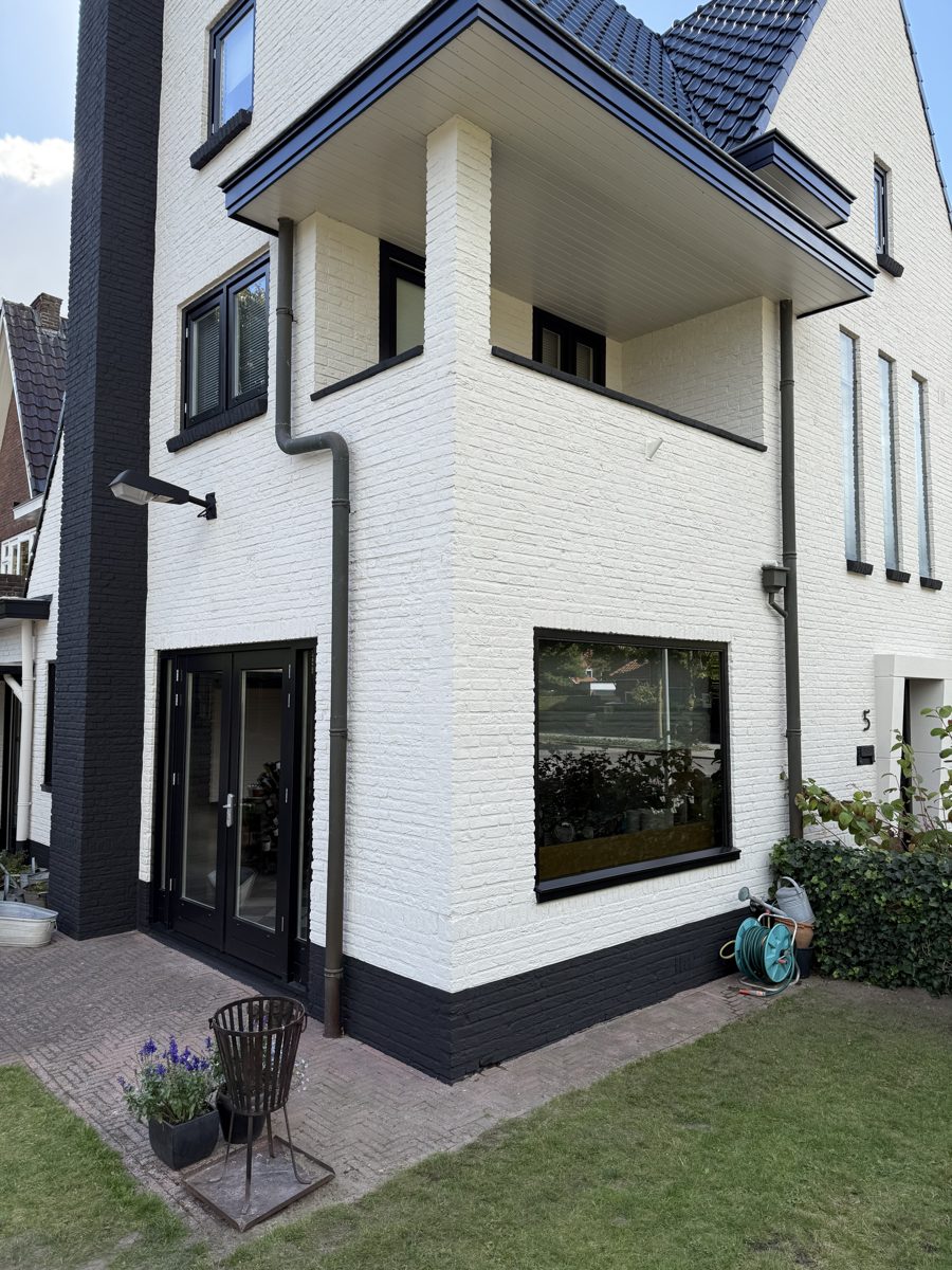 Wit gespoten gevel van een woning na gevelcoating